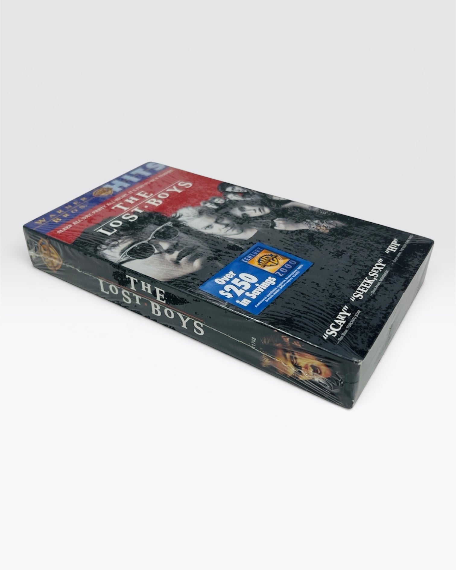 A sealed 'The Lost Boys' VHS tape, wrapped in clear plastic, photographed on a light gray background.