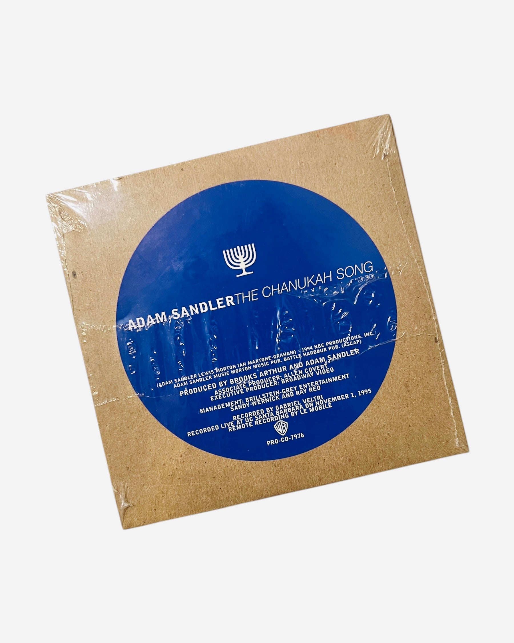 Vinyl record with blue label featuring Adam Sandler's 'The Chanukah Song' on a white background