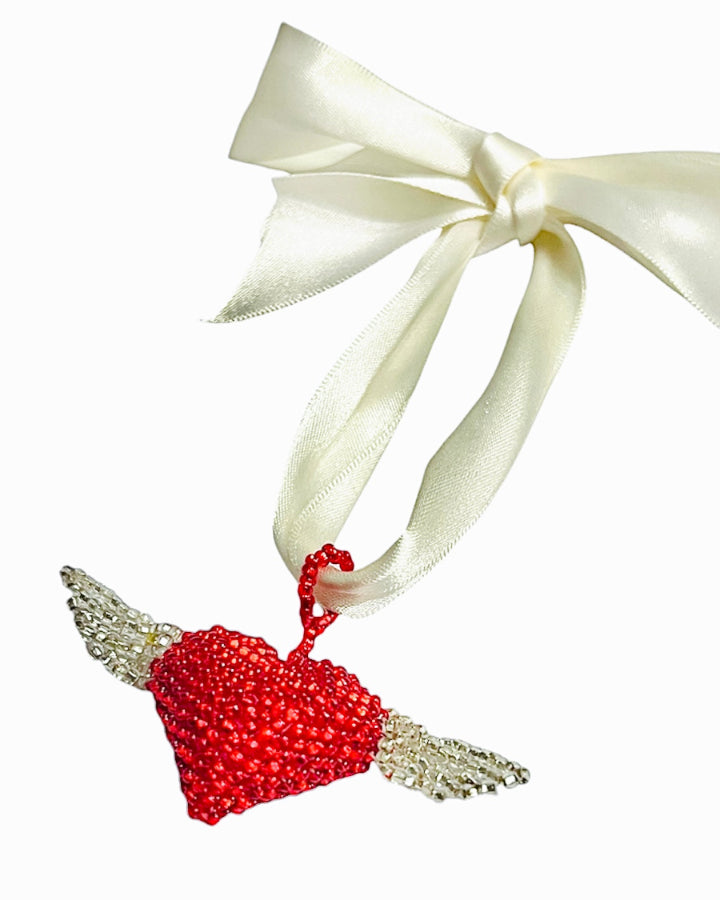 Red beaded heart ornament with a white ribbon on a white background